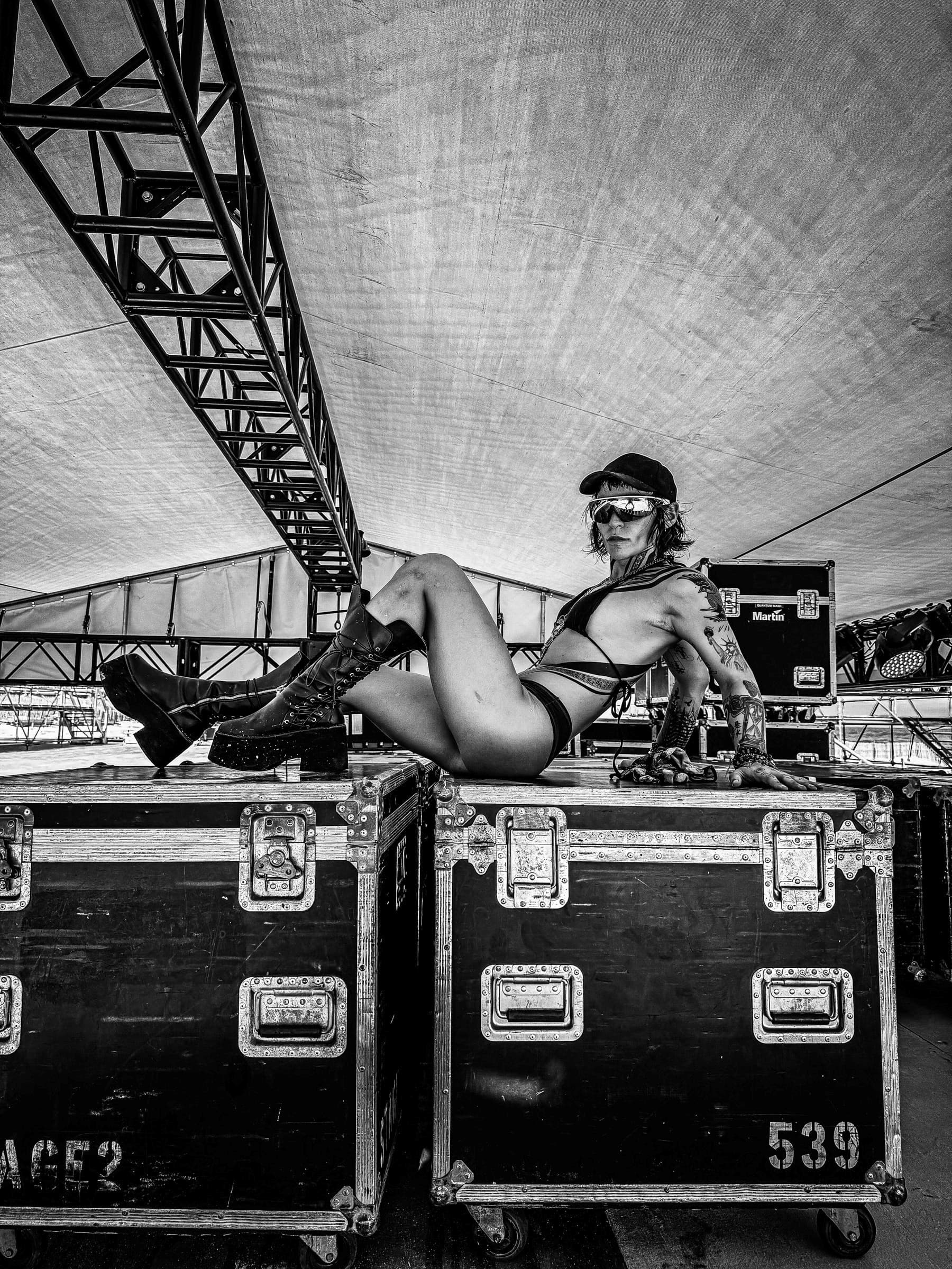 ZØ in the CRÜZØR PRAVAHA platform boots, lying across road cases under a stage truss